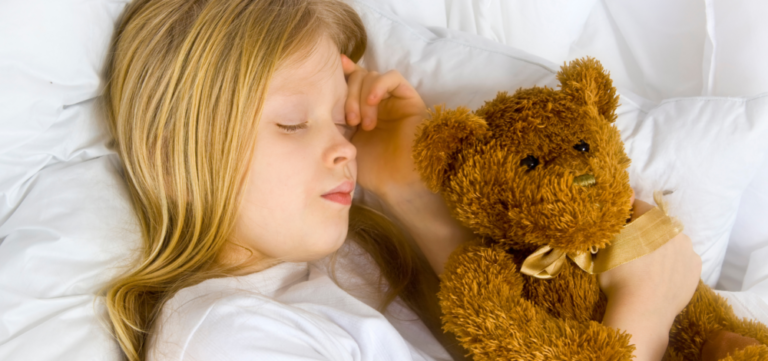 Young girl in bed sleeping with teddy bear