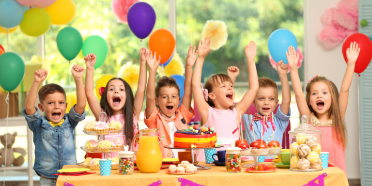 Childrens party with children at table with arms in the air