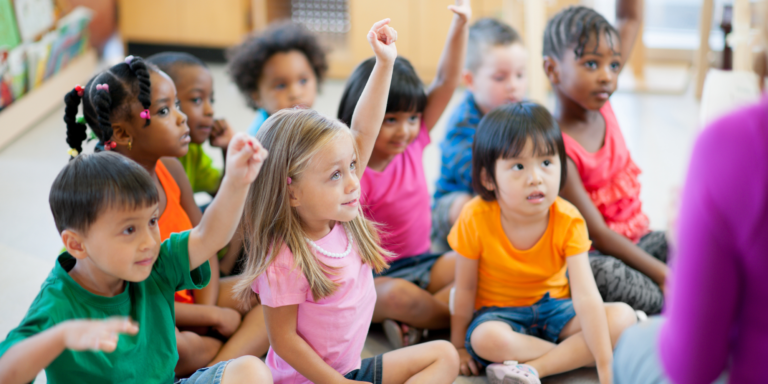 Preschool Music Program with children sitting with hands up